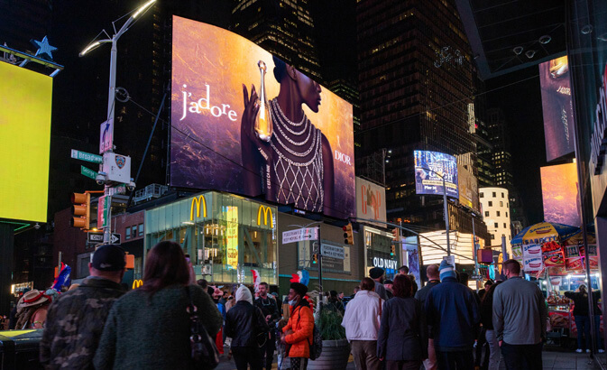 A view of Times Square. The large screen above the McDonalds has an ad for j'adore on it.