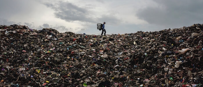 A photo of a person standing atop a massive mountain of trash