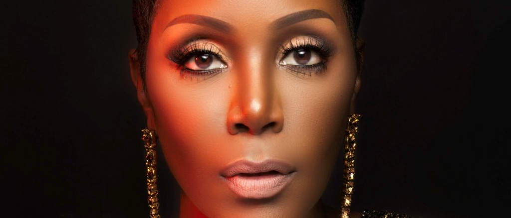 Close-up of Sommore wearing gold earings and a glittery gold top