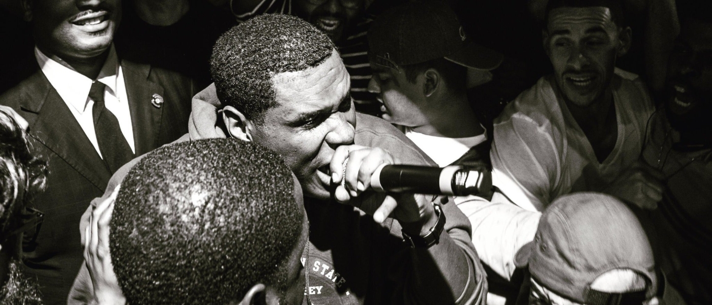 Black and white photo of Jay Electronica rapping in a crowd.
