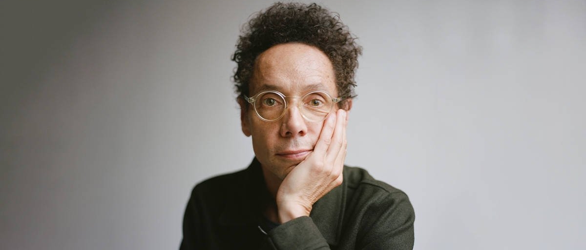 Malcolm Gladwell looking at the camera with his chin in his hand