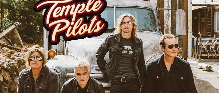 Stone Temple Pilots sitting on the grill of an old car