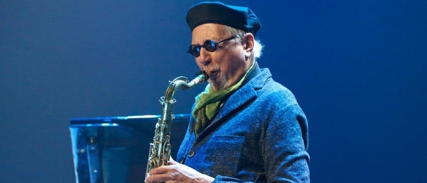 Charles Lloyd wearing a beret and playing the saxophone