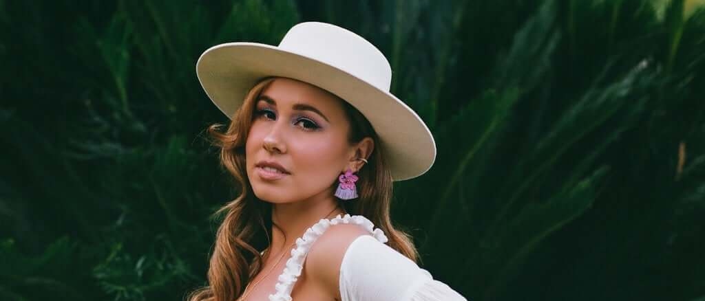Haley Reinhart in a white brimmed hat and a ruffled white bikini-style tied top.