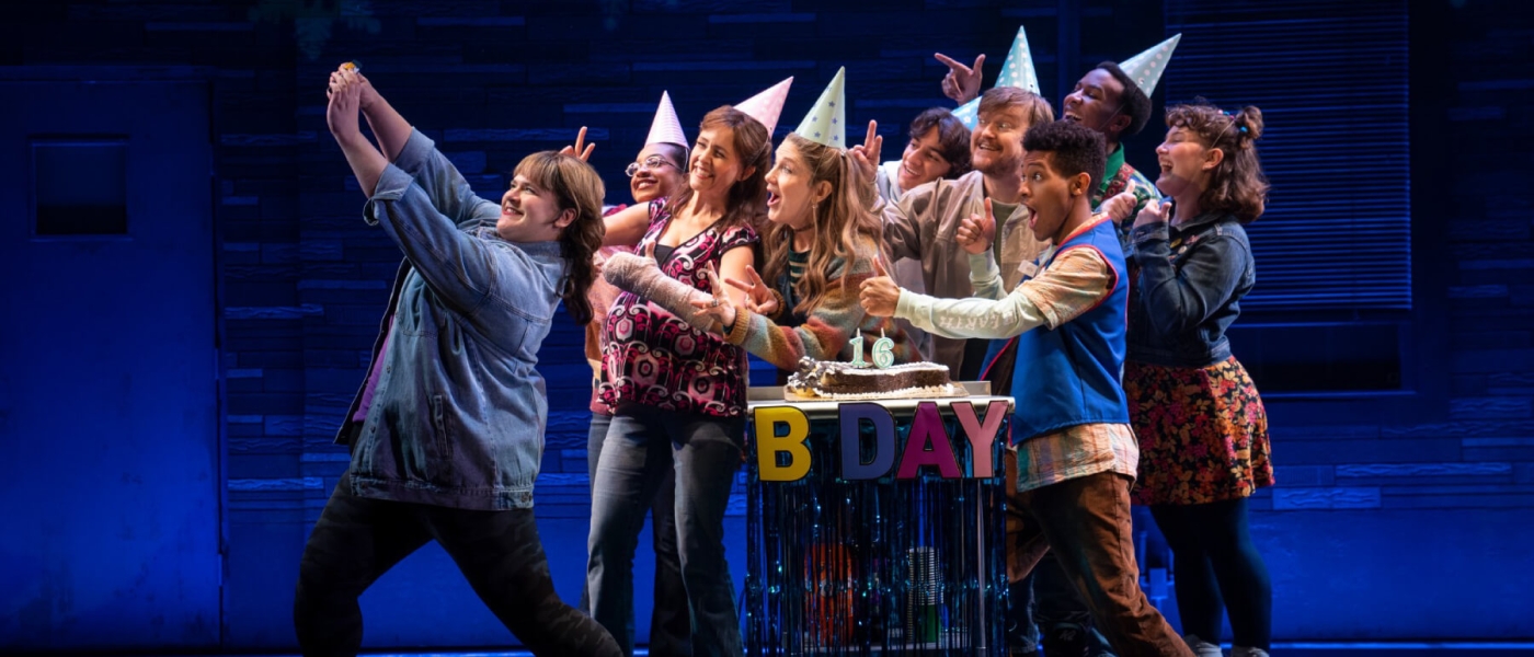 The cast of Kimberly Akimbo on stage taking a birthday party selfie in Act I