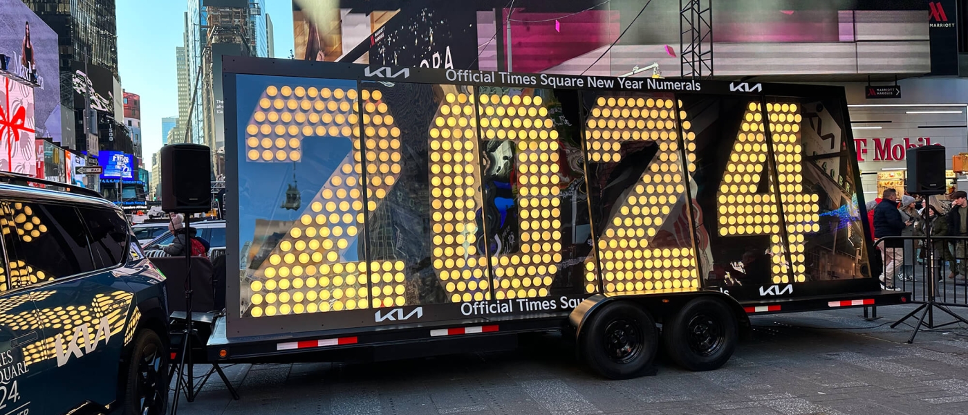A clear-sided trailer with the 7-foot tall numerals, covered in lightbulbs, reading "2024"