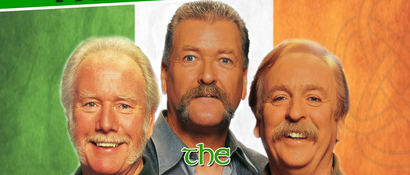 The members of The Wolfe Tones, three older white men with impressive mustaches, in front of an Irish flag background. Text reads "The Wolfe Tones"