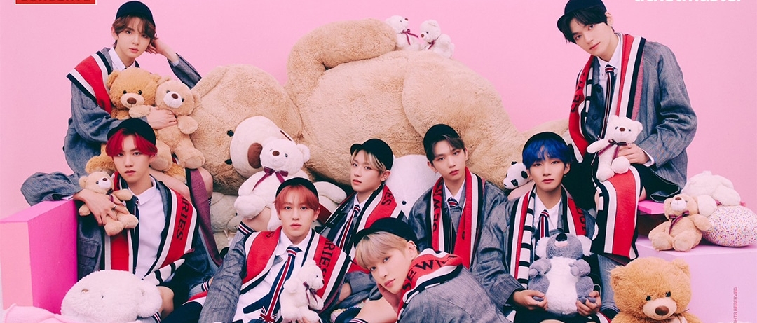 The eight members of EPEX wearing schoolboy outfits and sitting among stuffed animals