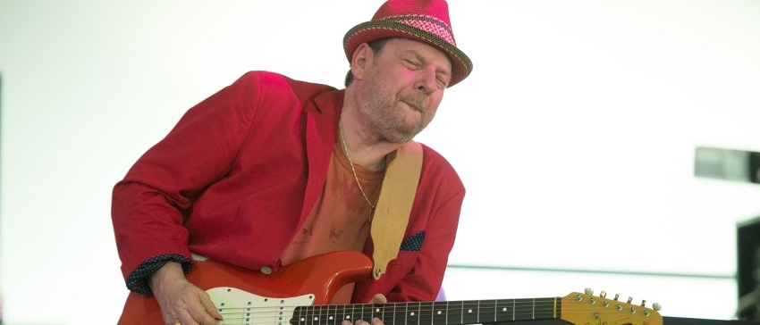Ronny Earl wearing a red suit and hat holding a red guitar