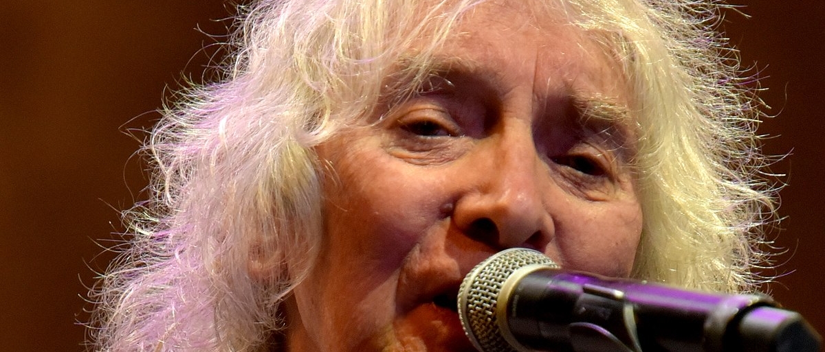 Albert Lee, an older white man with long white hair, singing into a microphone