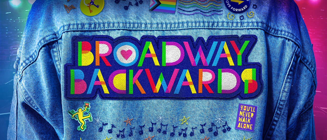 A jean jacket with rainbow embroidery reading "Broadway Backwards" along with several pride- and music-themed pins and embroidery