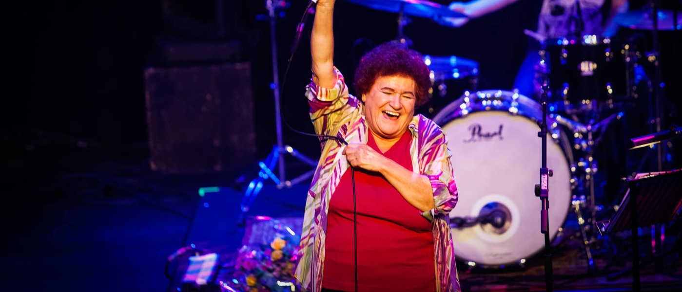 Selda Bagcan raising her microphone triumphantly while performing on stage
