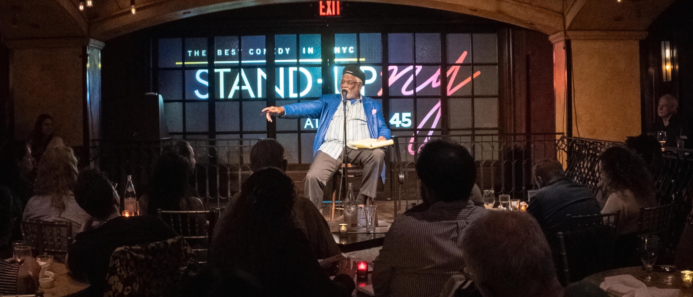 A comedian sitting down while performing a stand-up show at Bond 45