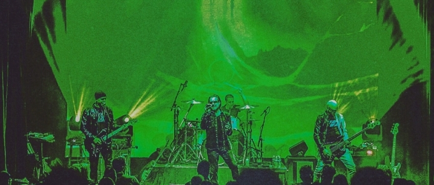 A green-tinted photo of Unforgettable Fire performing as U2