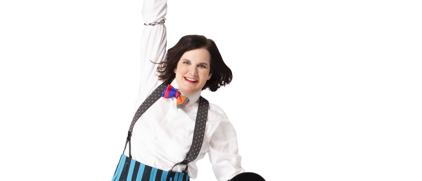Paula Poundstone jumping while wearing suspenders and a bowtie