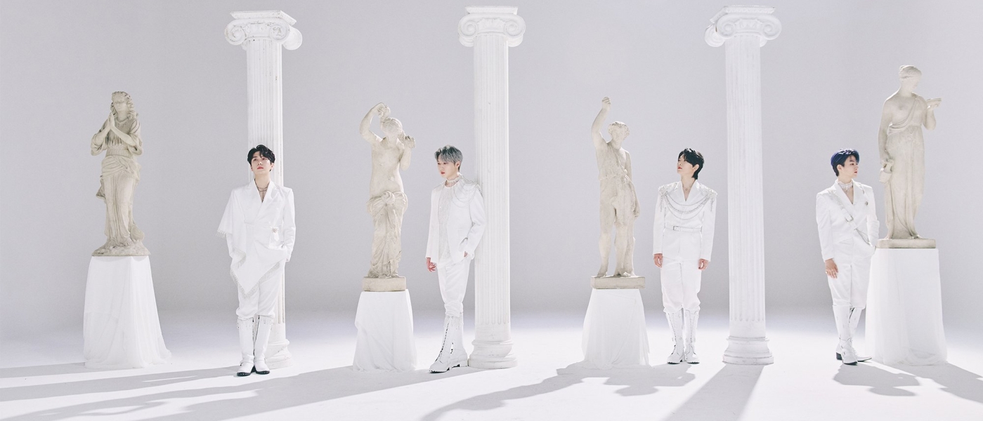 The members of Forestella all dressed in white in a room with columns and marble statues