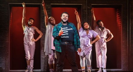The cast of A Strange Loop on stage. Usher wears a flannel shirt and a t-shirt with a bell hooks quote.