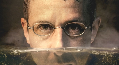 A promotional poster for An Enemy of the People on Broadway, showing Jeremy Strong with his face half-submerged in water