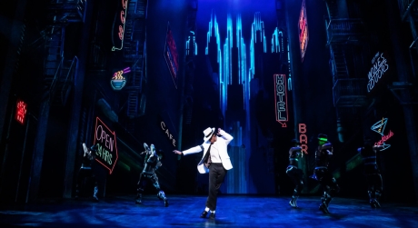 Myles Frost as Michael Jackson in the iconic white coat and white hat, with a cityscape background